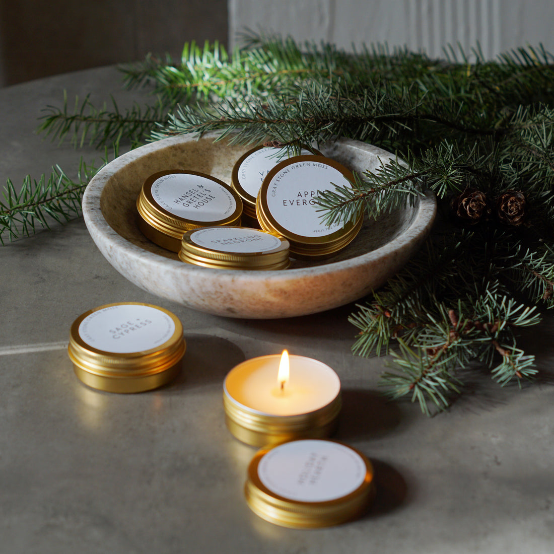 Introducing the Gray Stone Green Moss Winter Collection Candle Flight: A Festive Scented Journey in Gold Tins